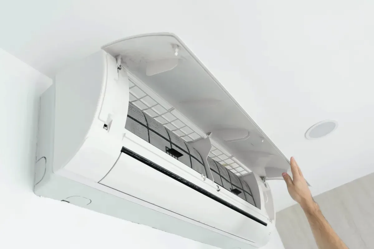 Hand opening the cover of a wall-mounted ductless air conditioner